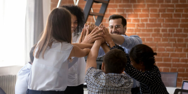 Positive multiracial millennial businesspeople colleagues giving high five feels happy achieved goal celebrating successful completion of project. Symbol and meaning of support togetherness and unity